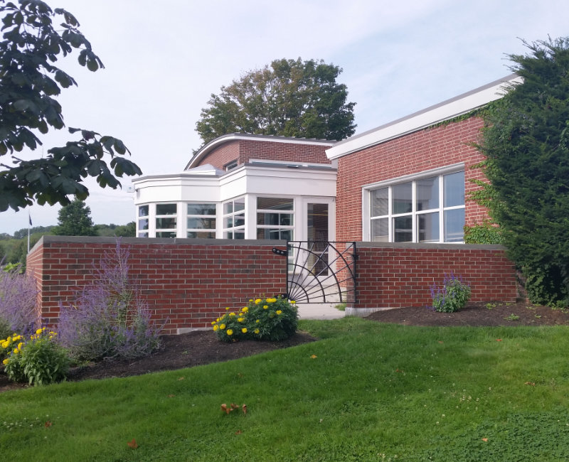 Brick building on a grassy hill for Libby Memorial Library