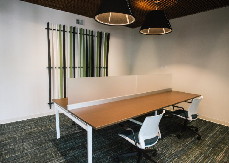 Large communal desk with two office chairs and glass separator