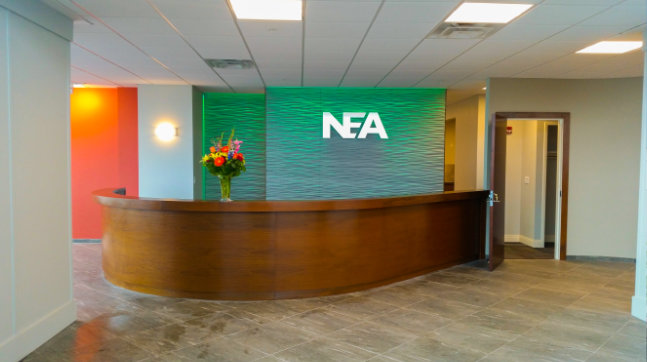 Front desk of NEA building with logo and green wall